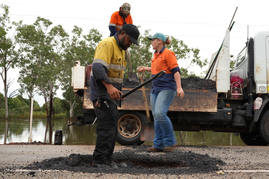Workers fix a whole in a bitumen road