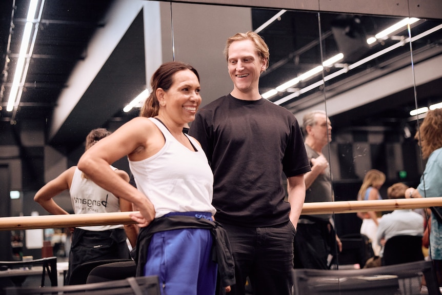 Frances Rings, an Indigenous woman, mid-50s, and David Hallberg, 43, in a rehearsal room. Hallberg smiles at a grinning Rings.
