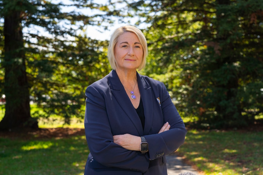 a blonde lady in a navy blazer with crossed arms