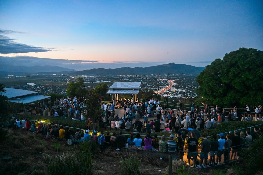 A gathering of people on a hilltop at dawn.
