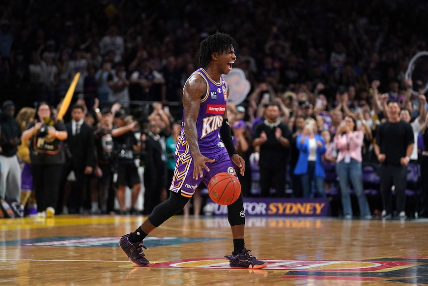 a basketball player on a court shouting in celebration