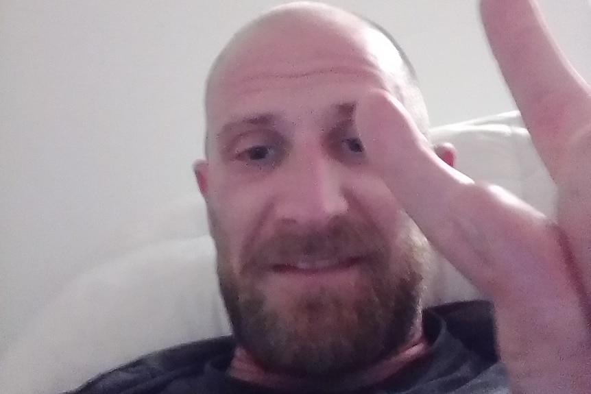 A man makes a peace sign with his hands in a selfie photo.
