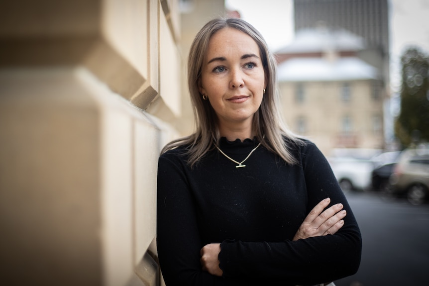 A woman leaning against a wall.