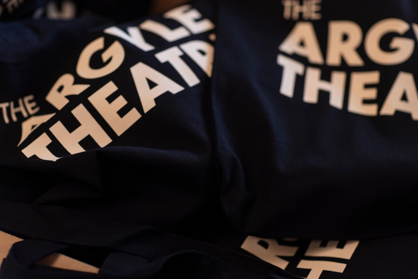 Black tote bags with The Argyle emblazoned across them on display.