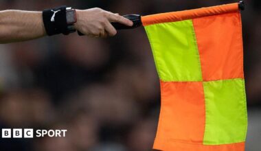 An assistant referee holds out a flag for offside