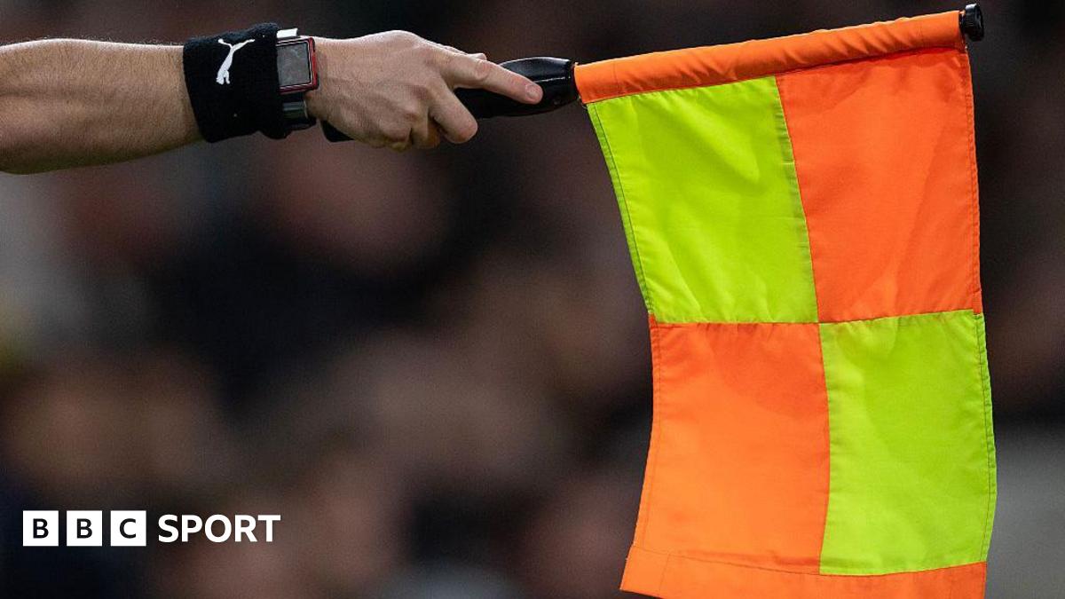 An assistant referee holds out a flag for offside