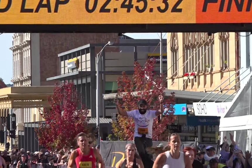 A man cheers as he runs on stilts