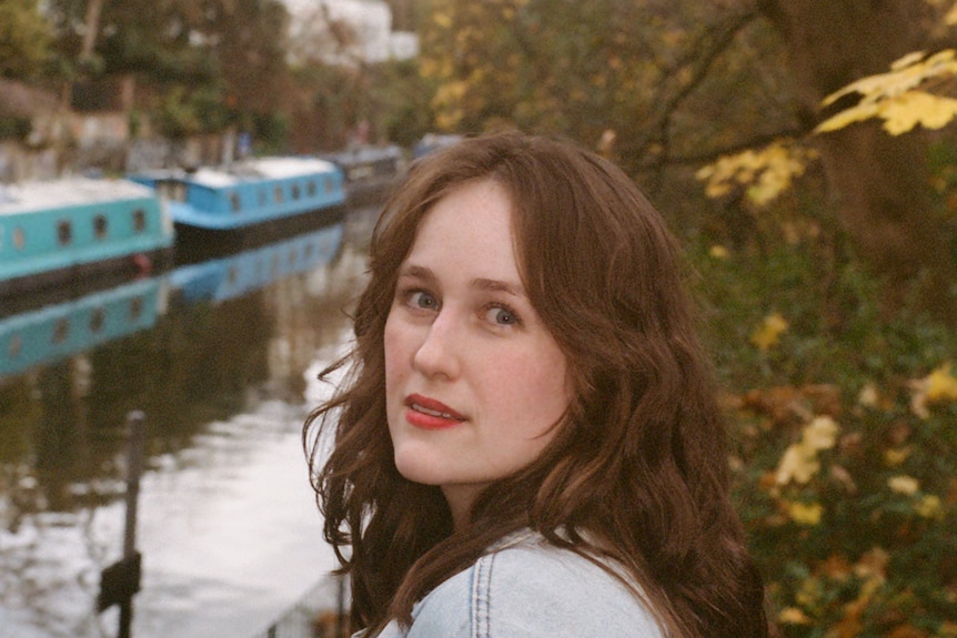 Grace smizes while looking back for a photo in front of a canal with house boats on it.