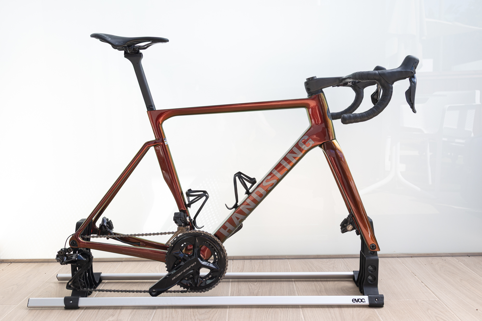 An orange bike frame mounted on a simple metal frame without wheels