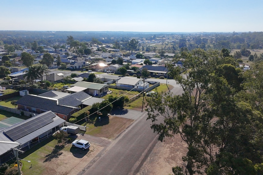 An aerial of housing, sea and hills in the background, trees in the foreground.