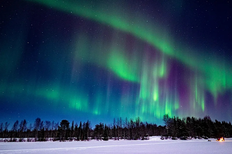 Very strong northern lights in green and purple on the nightsky. 