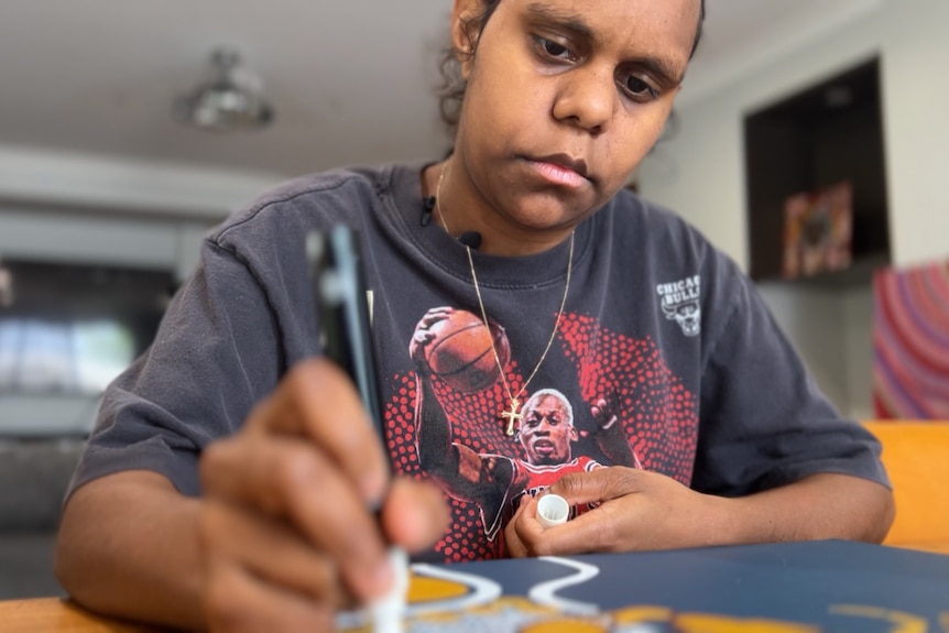 Keira creating an artwork at her kitchen table.