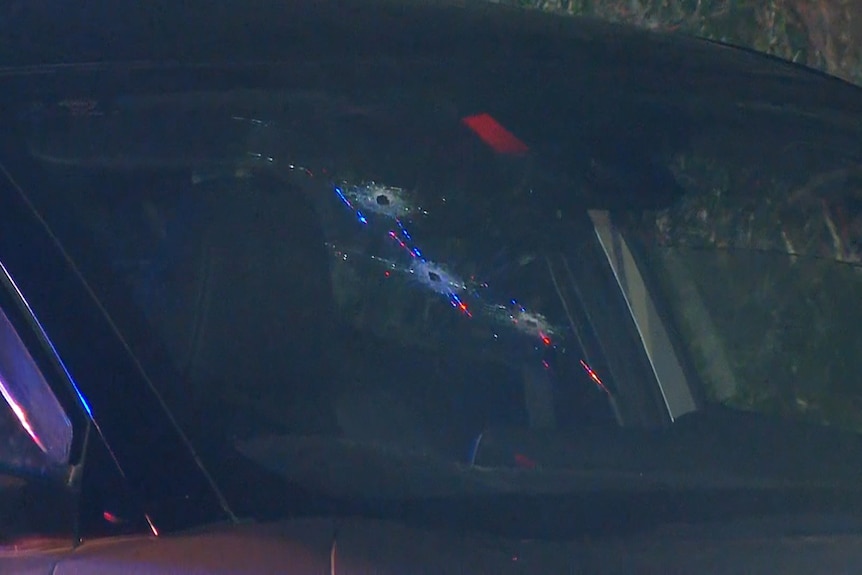 An up close of a car windshield with three bullet holes.
