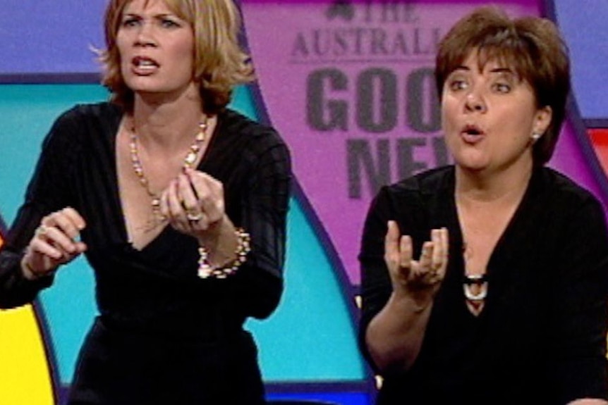 A TV still of Tracey Wickham, 36, and Julie McCrossin, 44, on a game show, making hand gestures to guess an answer.