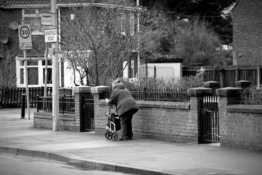 An elderly woman walks down an empty street.
