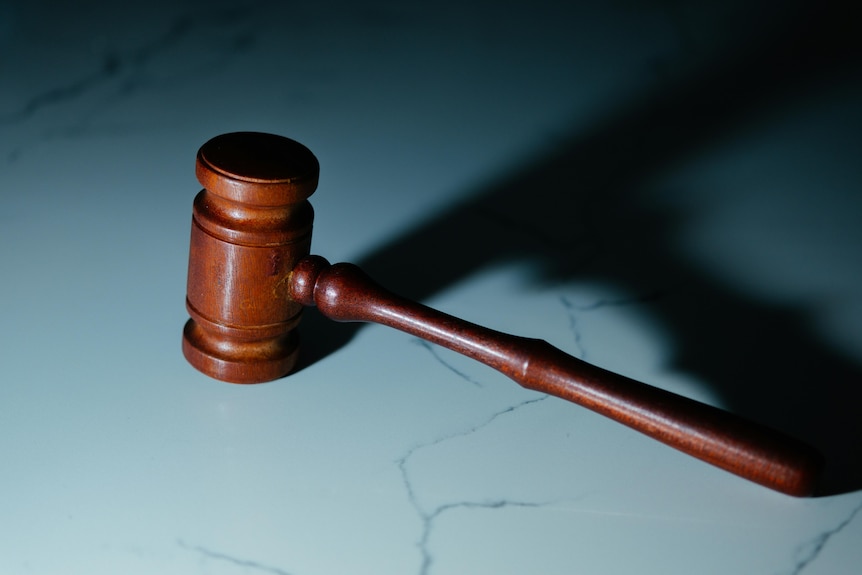 A photo of a brown judge's gavel, sitting on a flat surface.