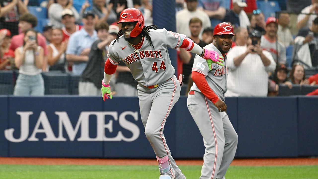 Cincinnati Reds' Elly de la Cruz (44) and third base coach Willie Harris celebrate de la Cruz's two run home run during the first inning of a baseball game against the Tampa Bay Rays Tuesday, April 21, 2026, in St. Petersburg, Fla. (AP Photo/Jason Behnken)
