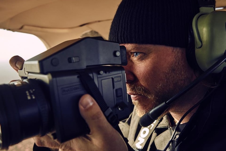 A close-up of a man holding a camera.