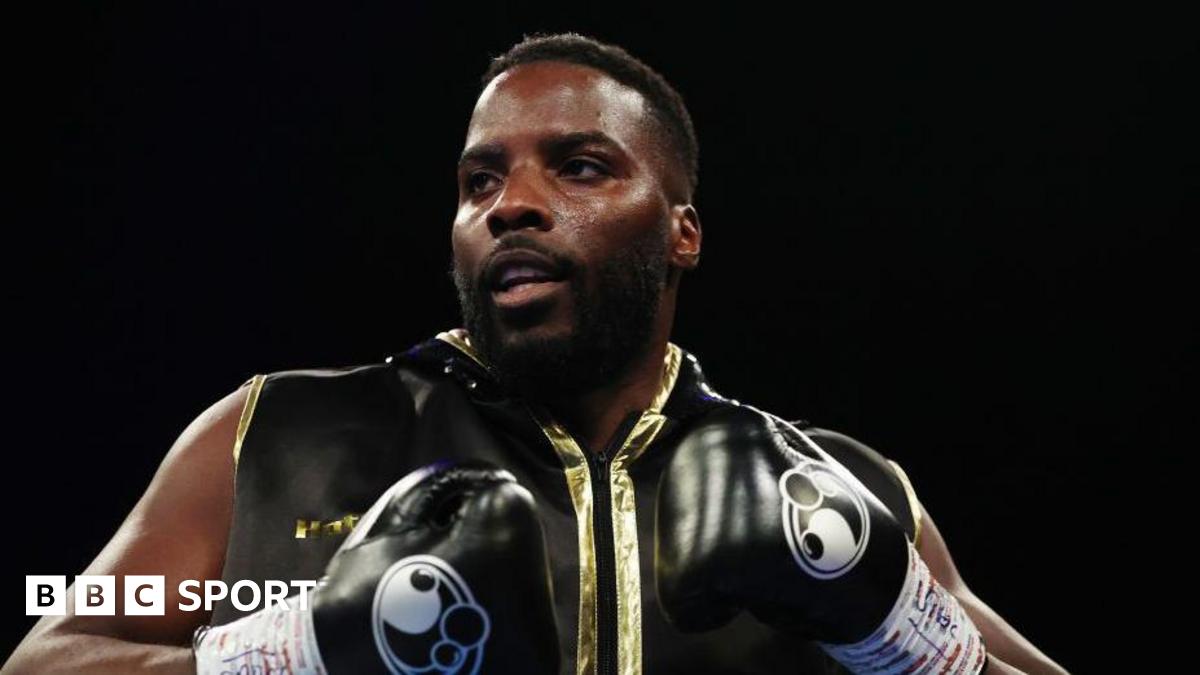 Lawrence Okolie in black boxing gloves and sleeveless black and gold zip-up top