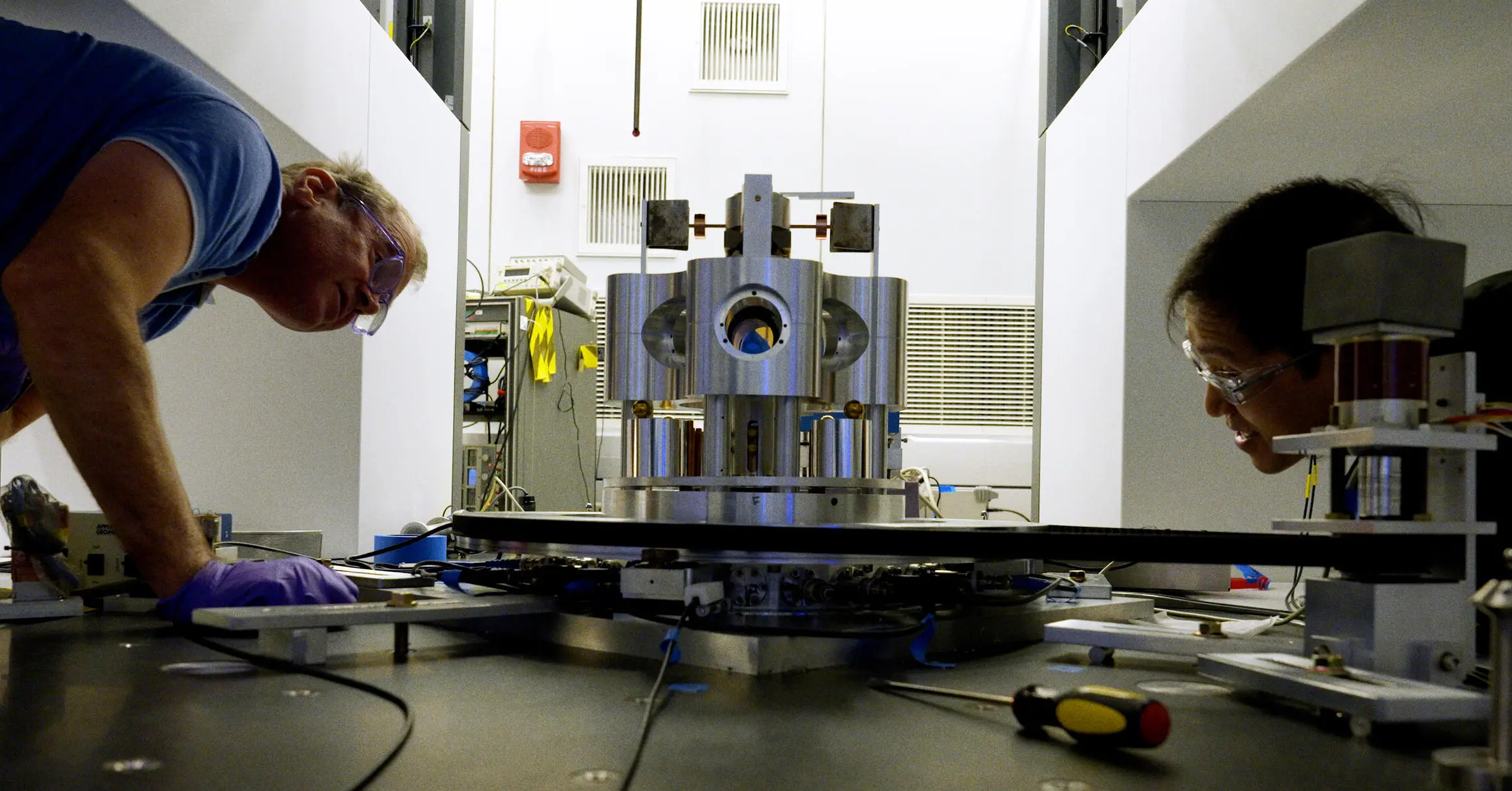 NIST scientists Stephan Schlamminger (left) and Vincent Lee examine the torsion balance they used to measure the gravitational constant.
