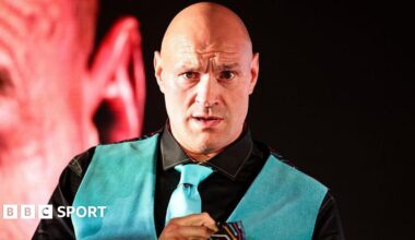 Tyson Fury looks on in a neon blue waistcoat and tie