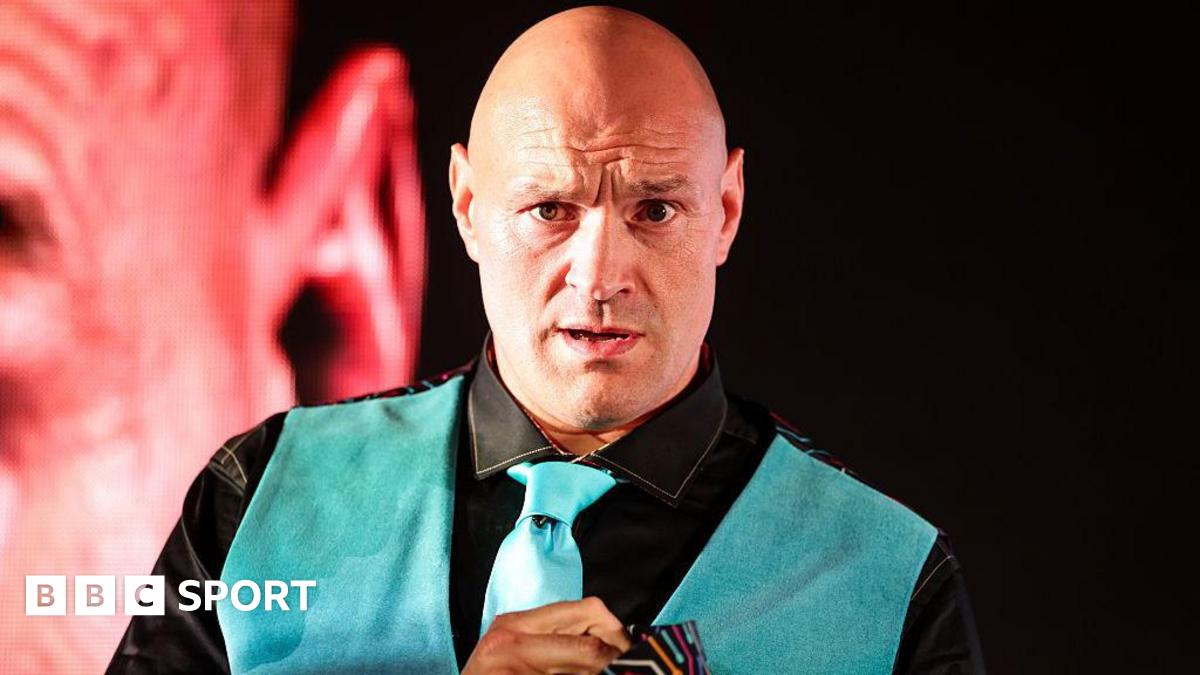 Tyson Fury looks on in a neon blue waistcoat and tie