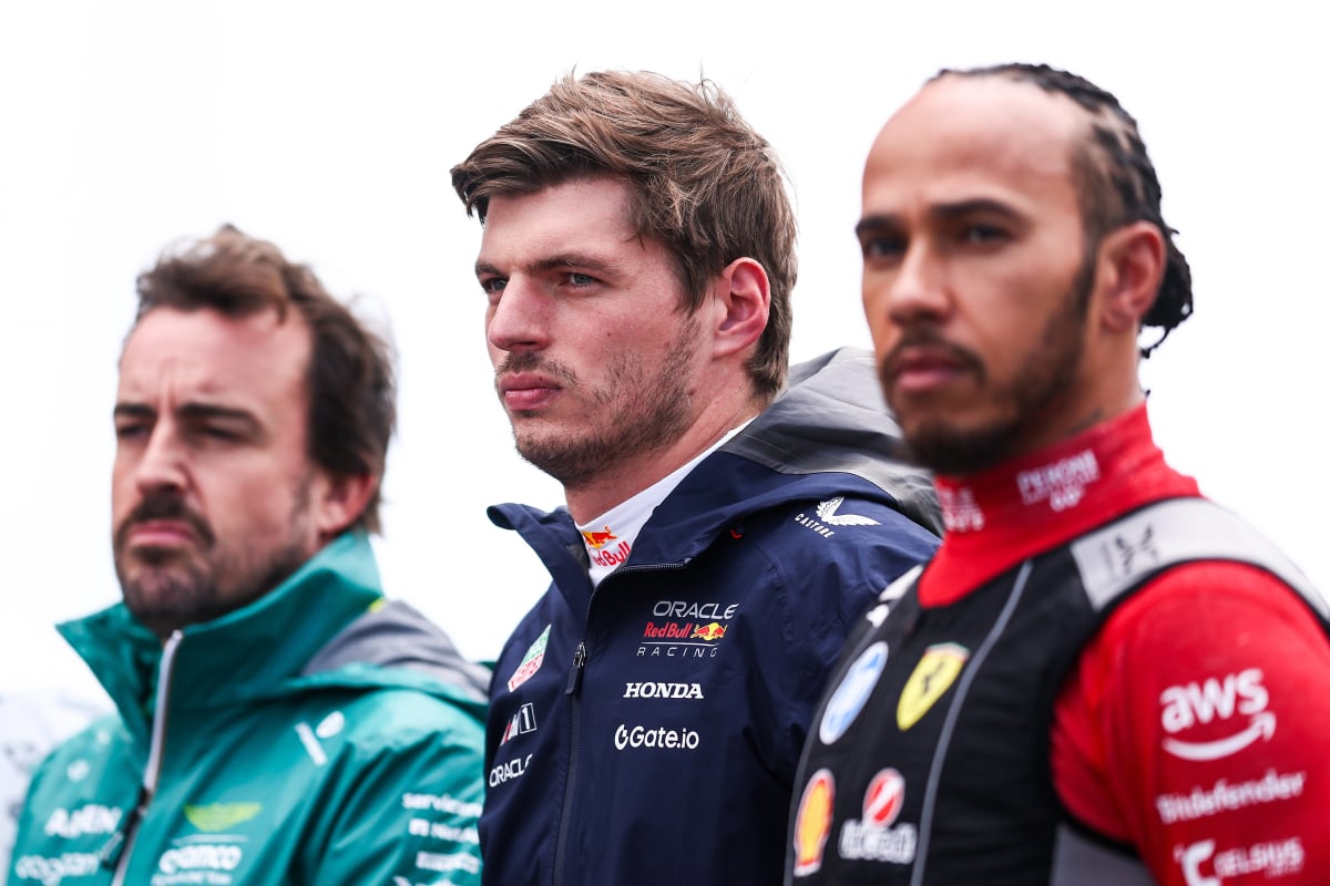 Max Verstappen and Fernando Alonso stand next to Lewis Hamilton