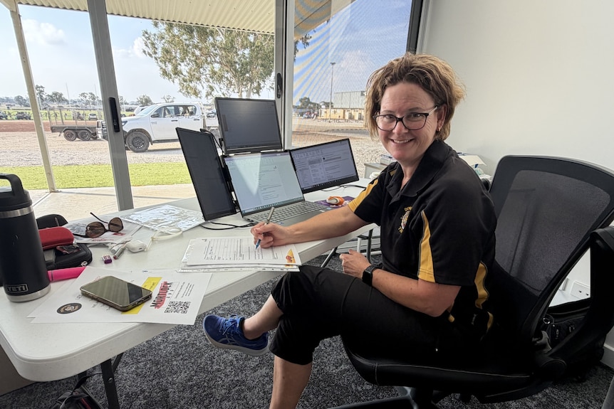 Tracy Jones sitting at her desk at the footy club.
