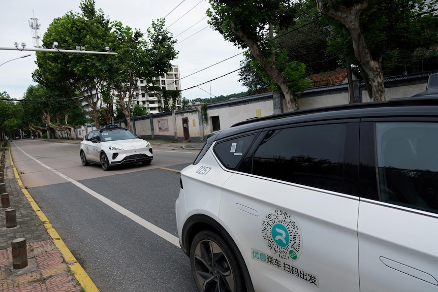 Two white cars on a road in China.