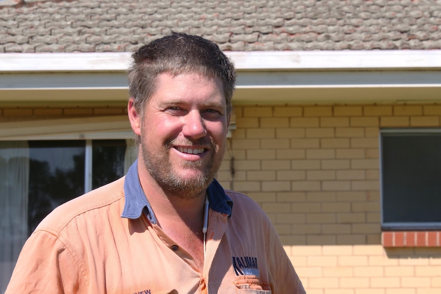 a man wearing an orange shirt smiling at the camera