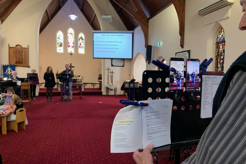 makeshift phone cameras pegged to music stand filming the service  