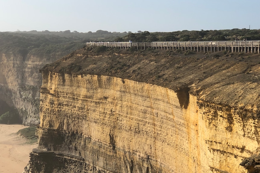 Sheer limestone cliffs drop-off above a beach.