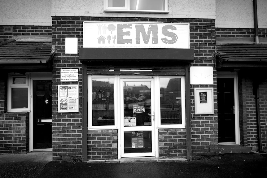 The exterior of a food bank with a sign saying they are open.