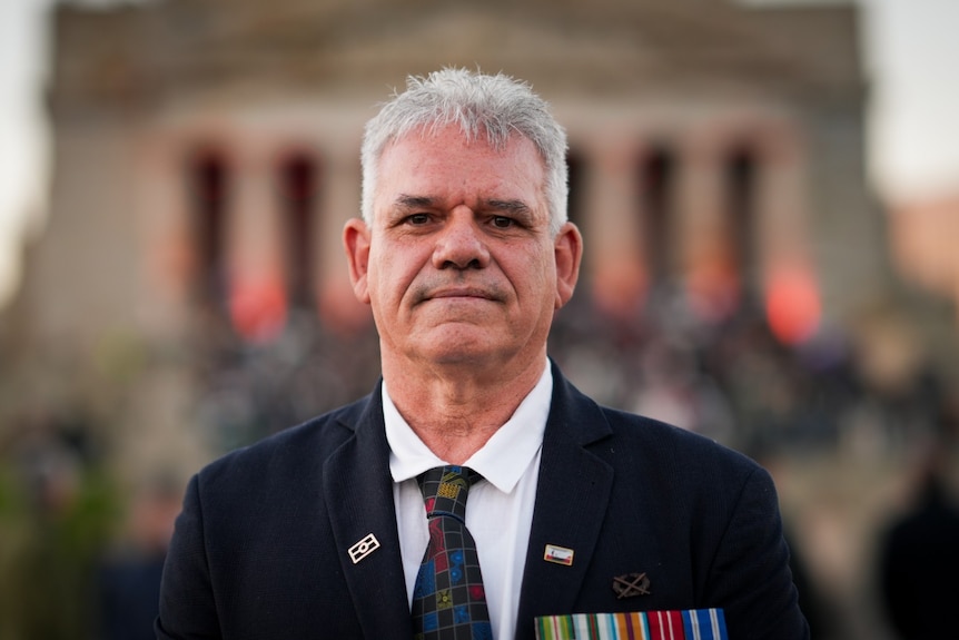A man wearing a suit and military medals looks ahead.