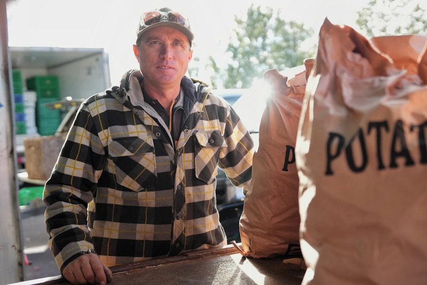 Luke smiles standing near a bag of potatoes.