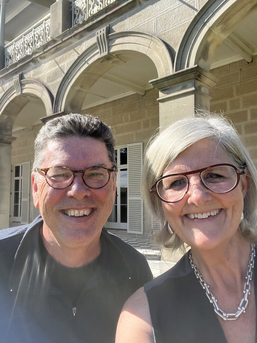 James Valentine and Sam Mostyn take a selfie outside of a large sandstone building.