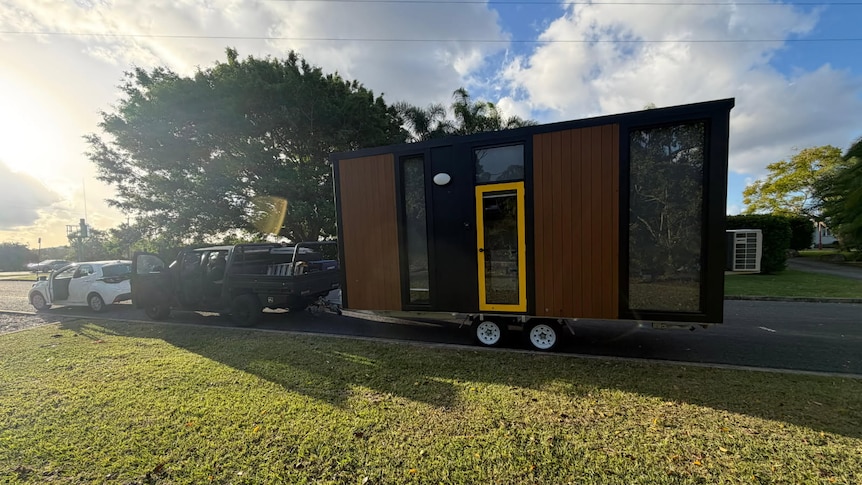 Tiny home on trailer towed by car.