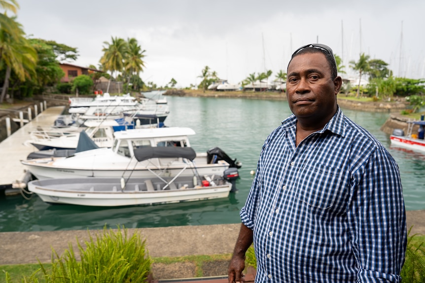 A man in front of boats at a marina.