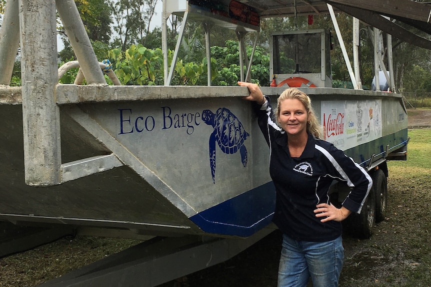 A woman leans on a metal boat.