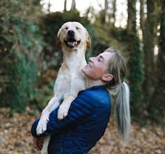 Woman carrying dog smiling