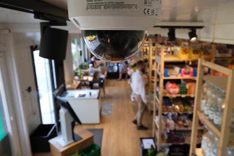 Spherical security camera in the foreground with a store in the background.