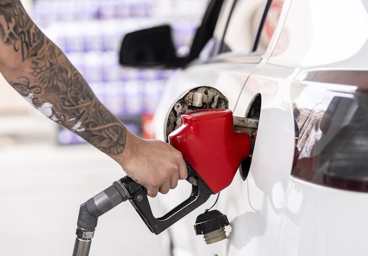 Close up shot of a person's hand holding a gas nozzle as they fill their car with gas