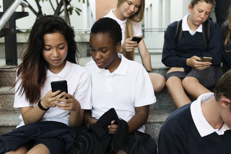 Group of children in school uniforms looking at phones