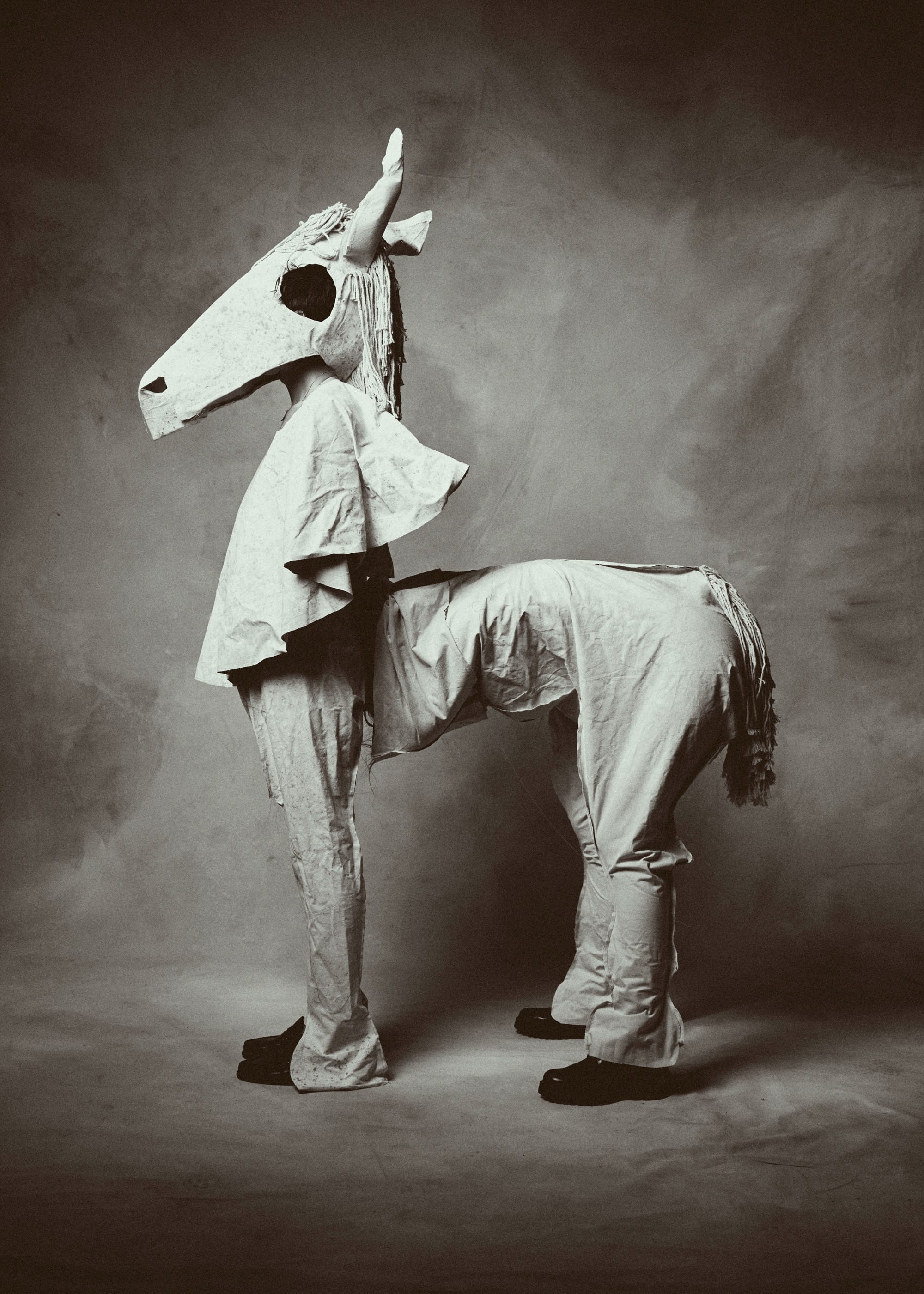 a black and white photo by Austn Fischer of two people in a crude horse costume