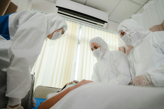 Healthcare workers in full protective gear attend to a patient in a hospital room, revealing hidden hospital truths.