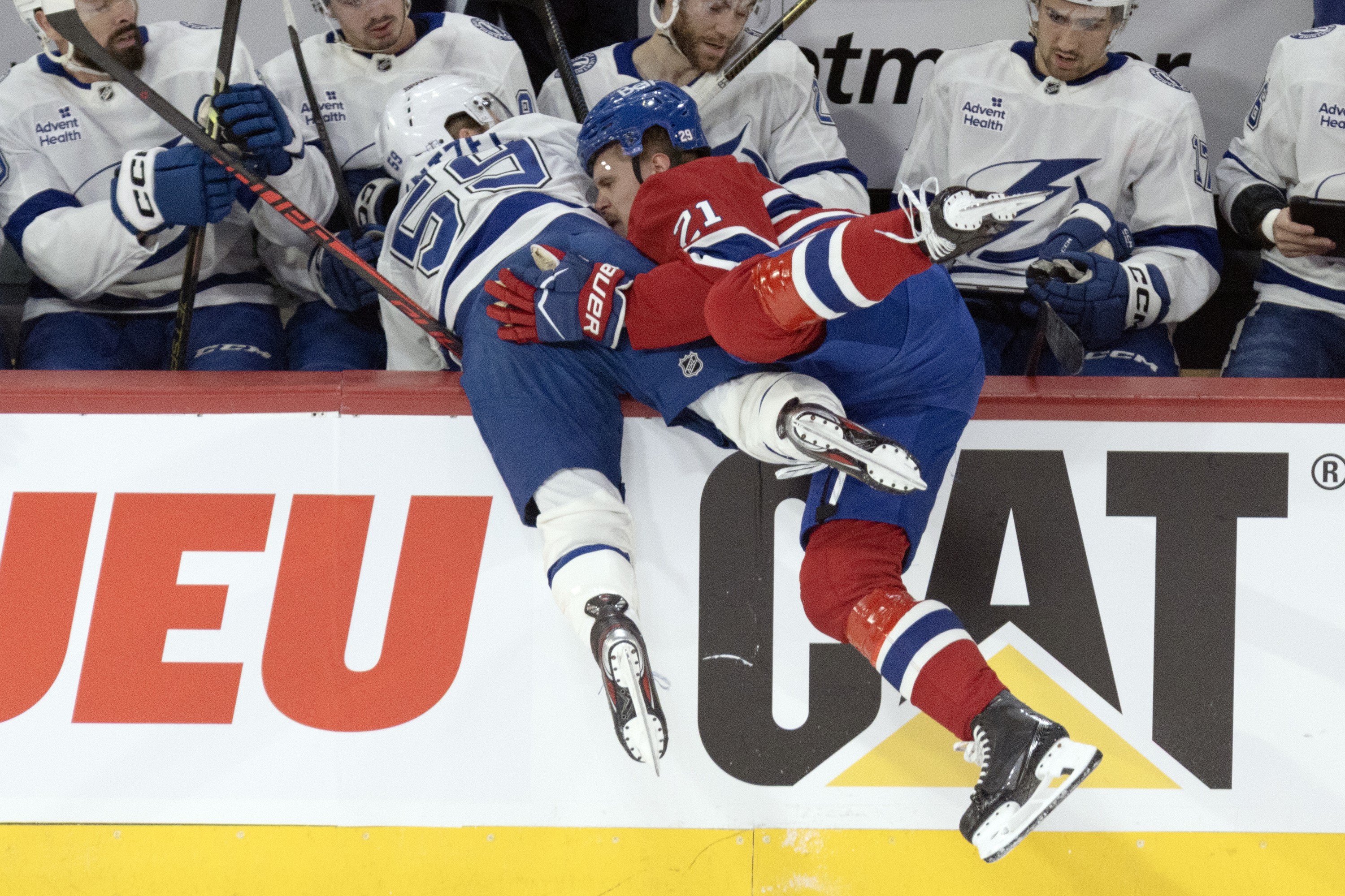 two hockey players falling into the bench