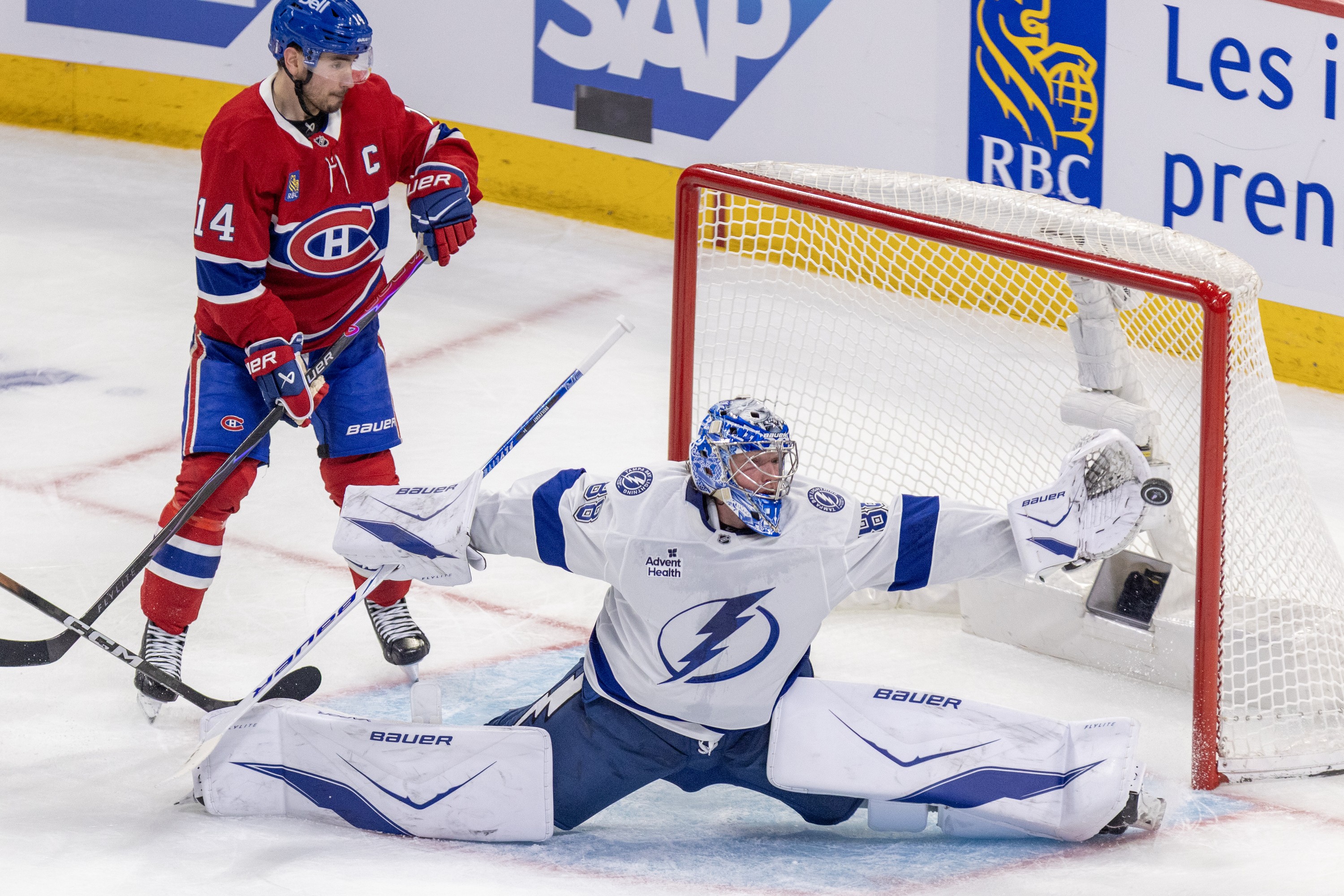 Lightning goalie Andrei Vasilevskiy stretches to make a save as Canadiens' Nick Suzuki watches.