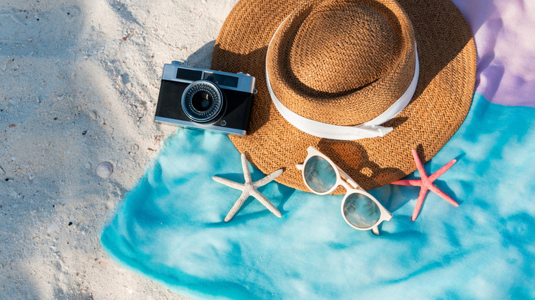 Several accessories on a beach towel on sand.