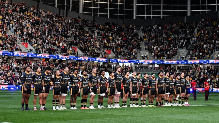 Hurricanes players stand during the national anthem in front of a packed Te Kaha Stadium before their victory over the Brumbies.