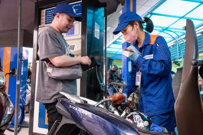 A woman fills a motorcycles fuel tank as the driver waits to pay at a gas station in Hanoi, March 7, 2026. Photo by VnExpress/Giang Huy